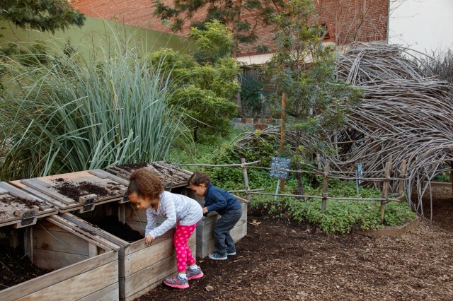 Girl and boy play with dirt in the Nature Gardens compost bins