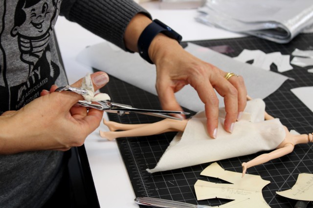 person cutting fabric on doll 