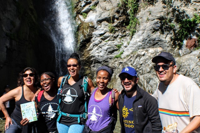 six people stand in front of a waterfall