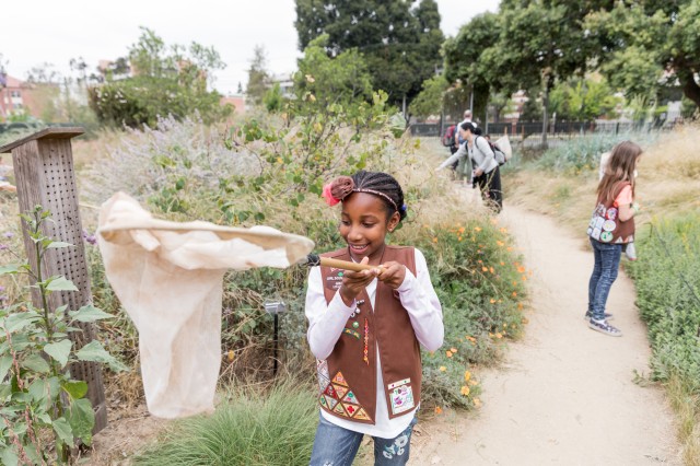 Child wearing a Girl Scout vest and holding a bug net