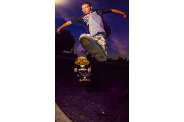 View of a skateboarder midair from below, with only one foot on the board.