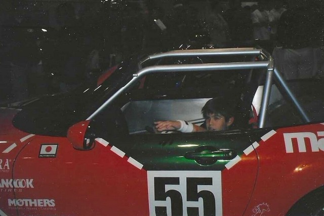 Young Charlie sits in a racecar version of the 2006 Mazda MX-5 Spec Miata