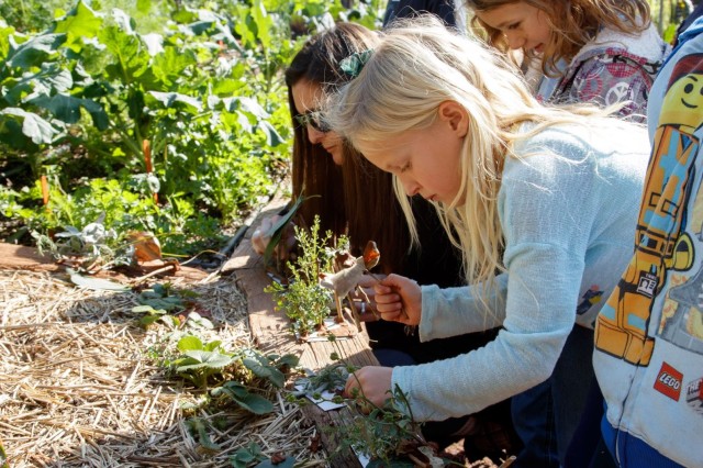 Children hovering overing dirt holding plant materials