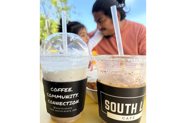 Father and young daughter sitting behind two iced coffee drinks with South LA Cafe logos on the cups.