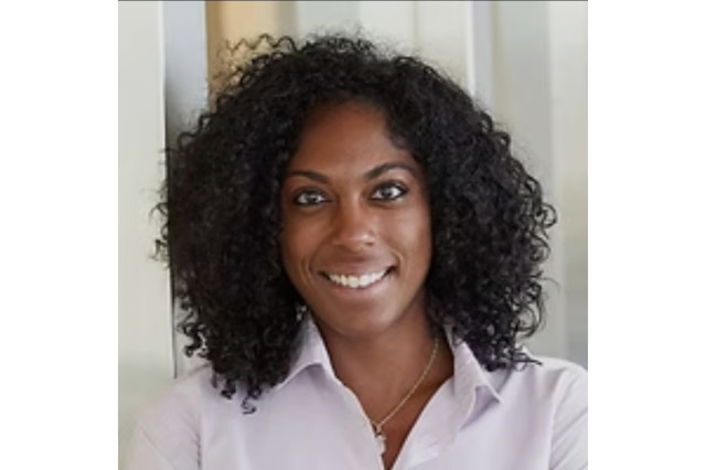 A curly-haired woman of African American descent poses for a business headshot.