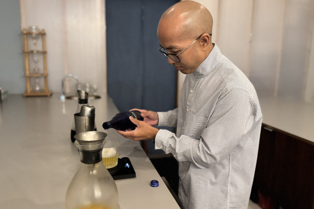 Man pouring mineral water into an artisanal glass of coffee.