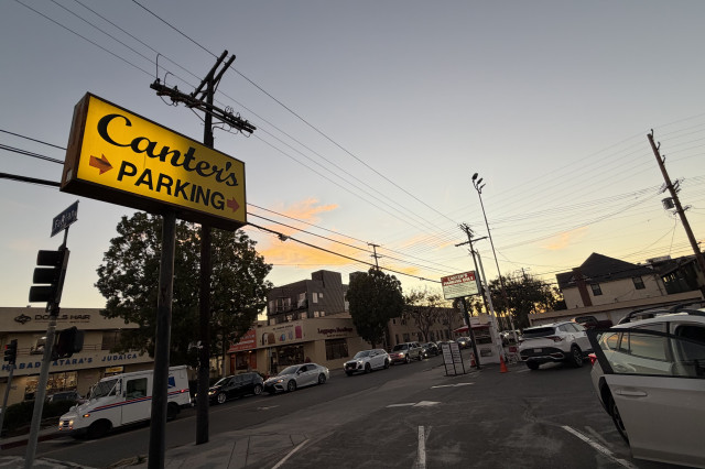 Canter's Parking sign above a small parking lot with the sunset in the background.