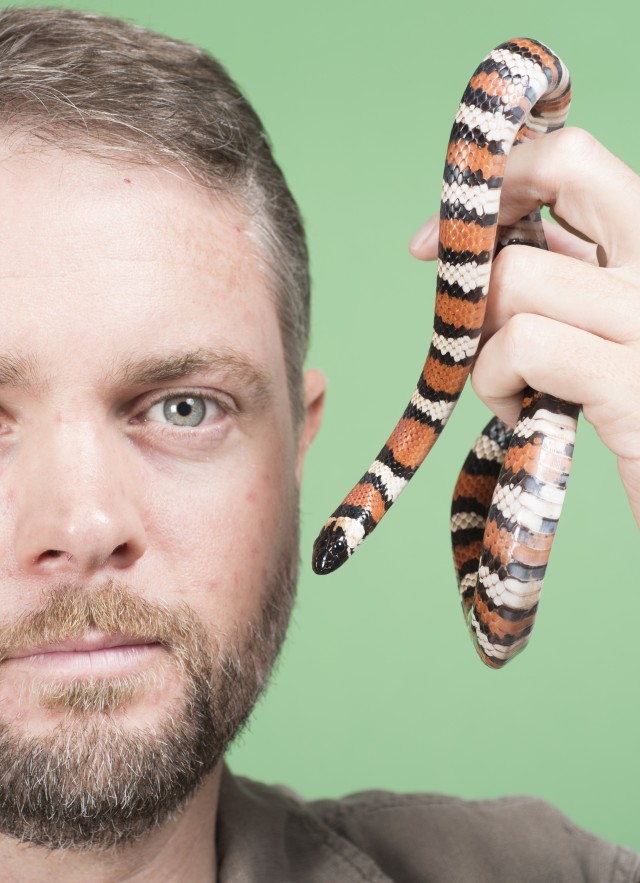 Dr. Greg Pauly with a snake in front of a green screen.
