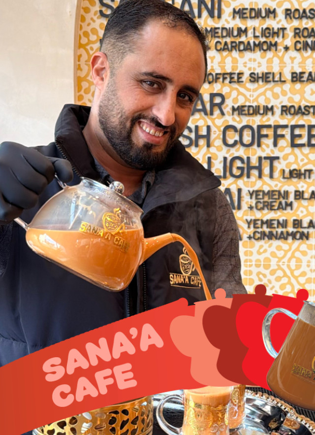 A man in a black vest and gloves smiles while pouring spiced tea from a glass teapot at Sana’a Cafe. The background features a patterned menu of Yemeni coffee and tea, with a red promotional banner in the foreground.