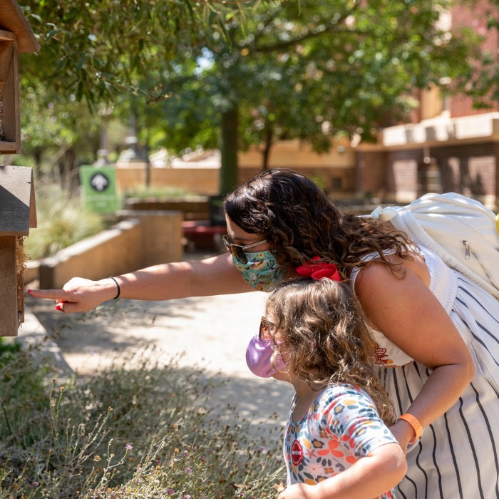 Member mother and daughter looking at bug hotel in nature gardens