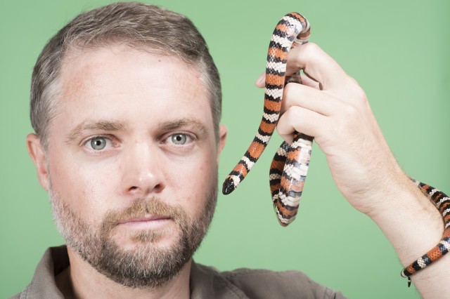 Dr. Greg Pauly with a snake in front of a green screen.