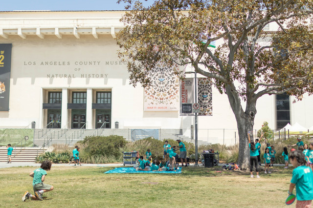 Children playing on the lawn in front of the Natural History Museum building
