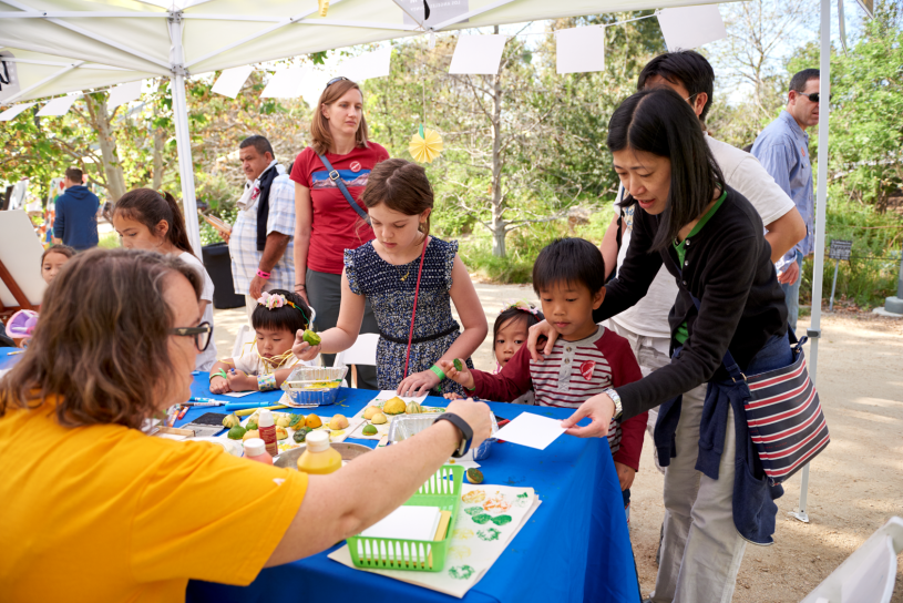 Families visiting an educational booth outside under a tent