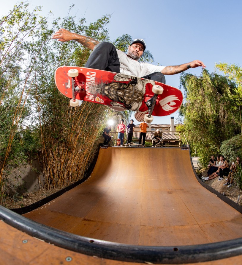 Skateboarder skating on a half pipe while his friends look on.